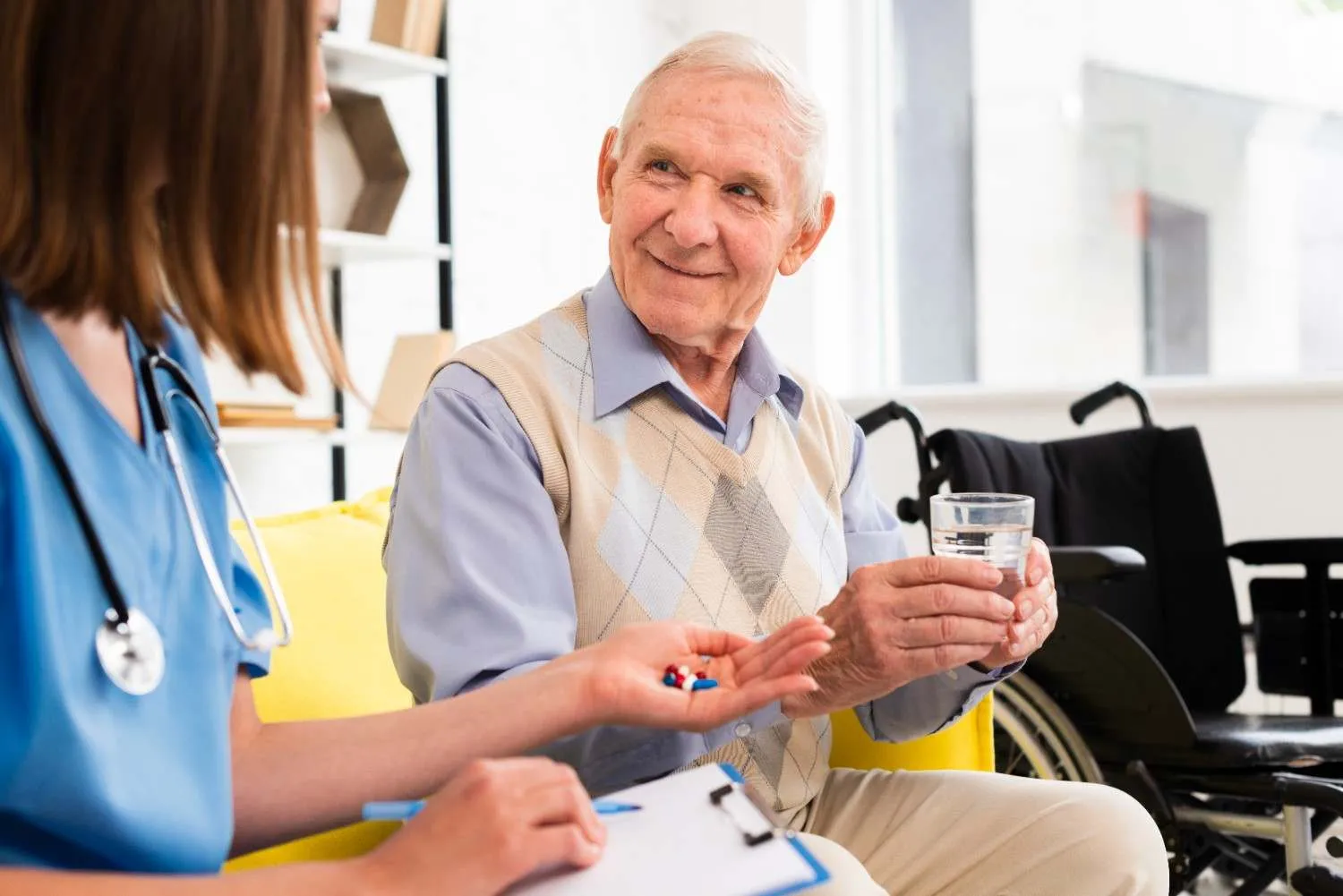 Nurse handing an older man his medication with a glass of water